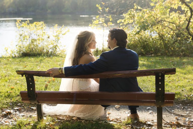Bride and groom on a bench in the sun.
