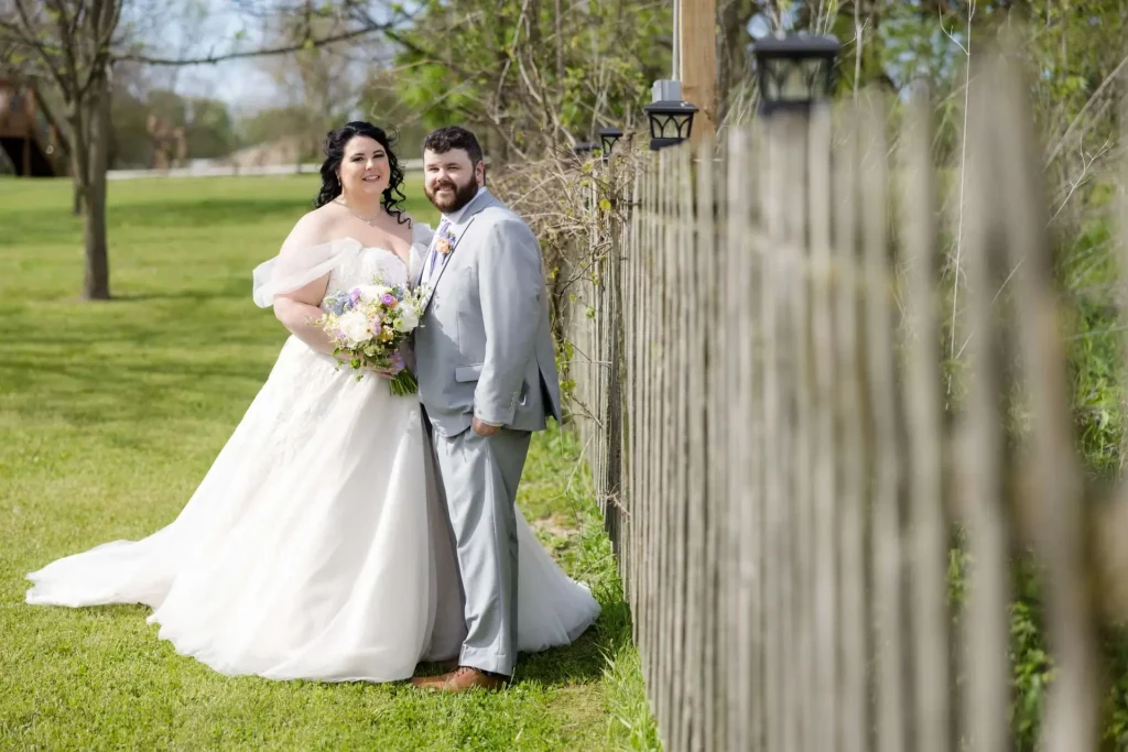 couple near fence at Vintage Rose Barn - Kalamazoo wedding photographer