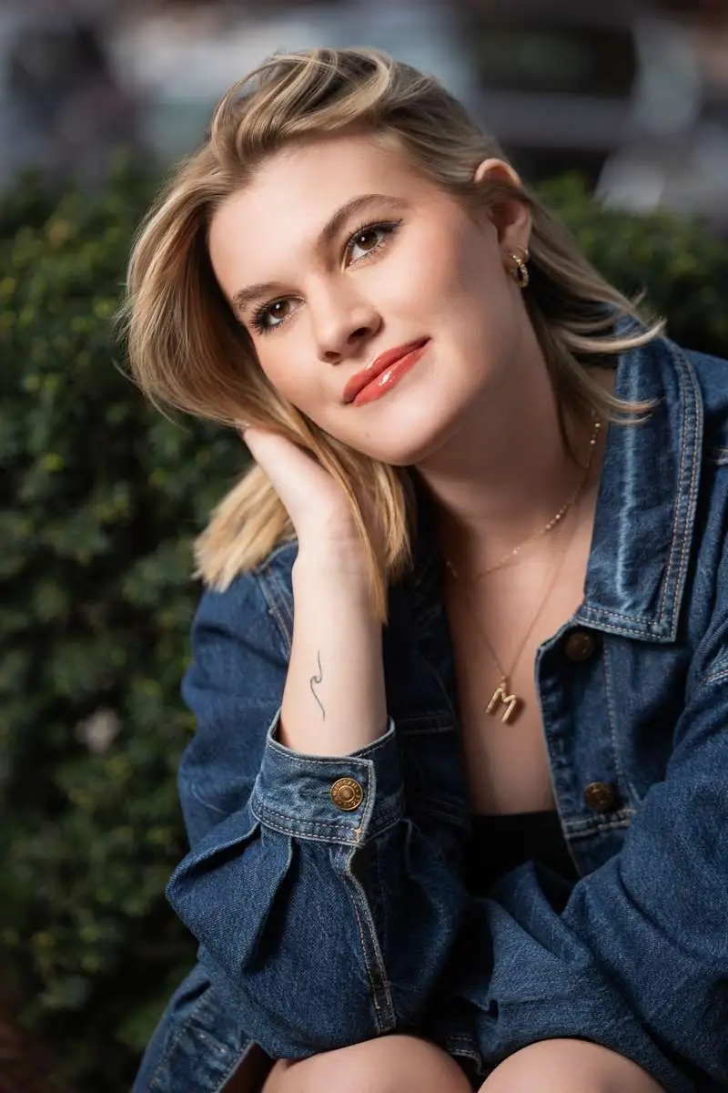 Kalamazoo high school senior posing in a denim jacket for a natural outdoor senior portrait